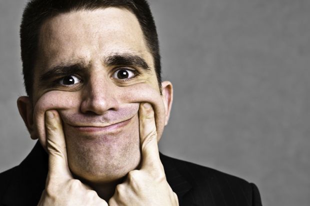 Man pulling face into fake smile Man pulling face into fake smile