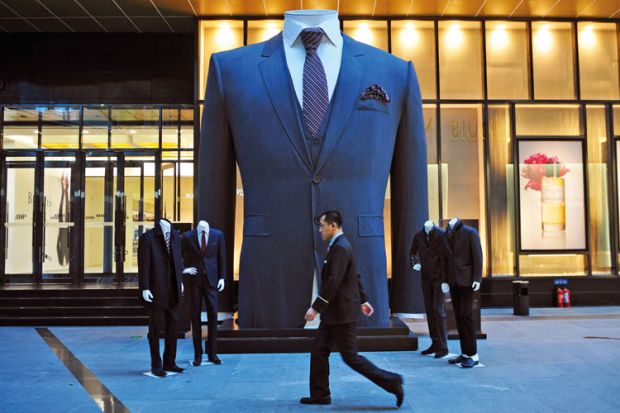 Man walks past huge suit, Shenyang, Liaoning province Man walks past huge suit, Shenyang, Liaoning province