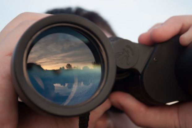 Man looking through binoculars illustrating op-ed by Stephen Toope about University of Cambridge principles around international engagement