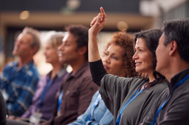 A mature student raises her hand in a class