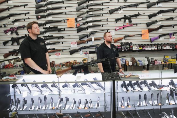 Men stand in front of display of firearms in gun store, Lake Barrington, Illinois Men stand in front of display of firearms in gun store, Lake Barrington, Illinois