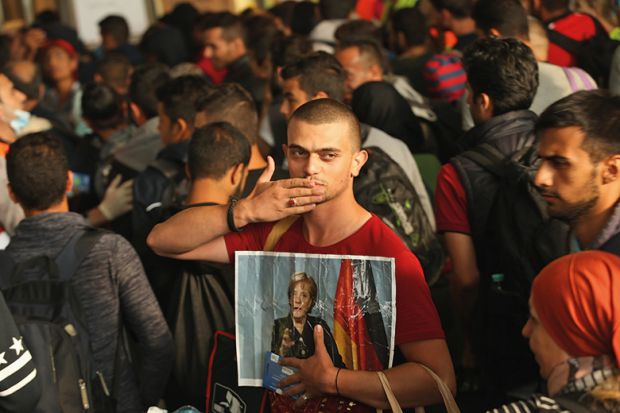 A migrant from Syria holds a picture of Angela Merkel A migrant from Syria holds a picture of Angela Merkel