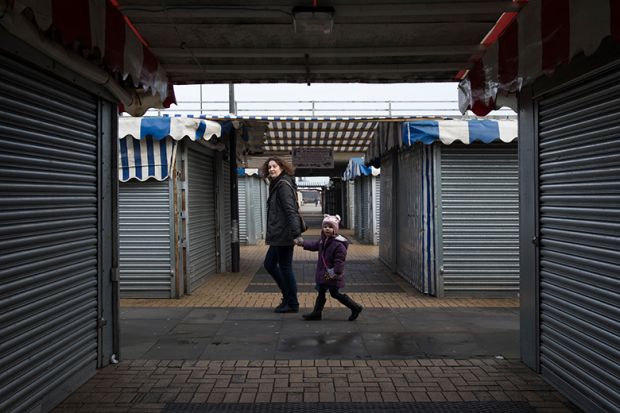 A woman and child walk through a market area with closed stalls in Milton Keynes, England.
