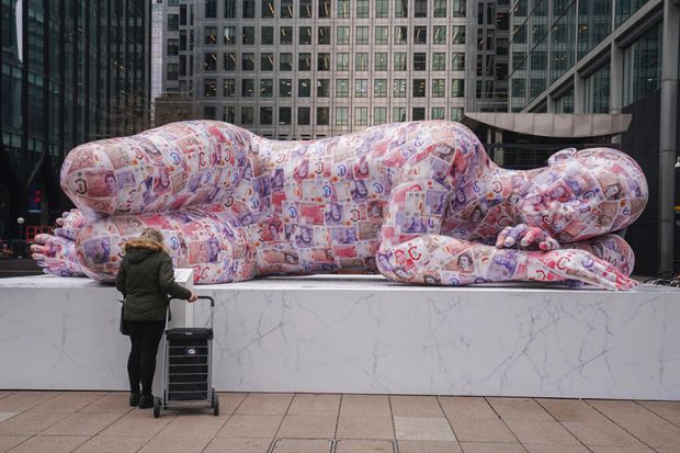 A sleeping giant sculpture made of recycled polystyrene and measuring 8 metres in length and covered in two thousands fake banknotes is installed in Canary Wharf, Docklands. To illustrate bonuses made to vice-chancellors. A sleeping giant sculpture made of recycled polystyrene and measuring 8 metres in length and covered in two thousands fake banknotes is installed in Canary Wharf, Docklands. To illustrate bonuses made to vice-chancellors.