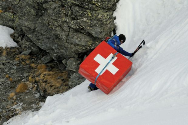 Mountain climber carrying safety mattress bearing Swiss flag Mountain climber carrying safety mattress bearing Swiss flag