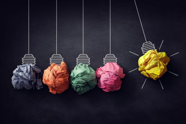 A Newton's cradle with crumpled paper lightbulbs, one of which is lit, symbolising ideas for efficiency