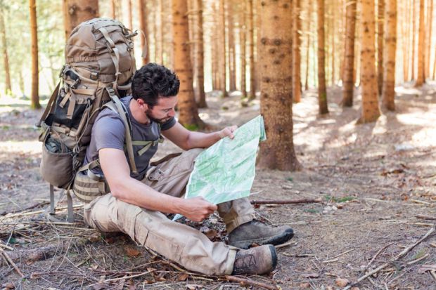 Outdoorsman/hiker sitting and reading map Outdoorsman/hiker sitting and reading map