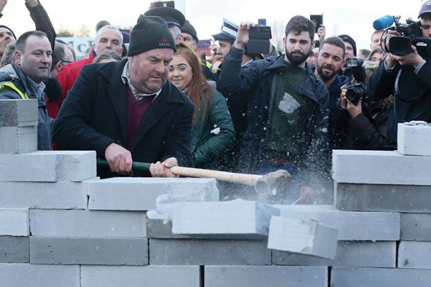 Protesters smash through mock wall