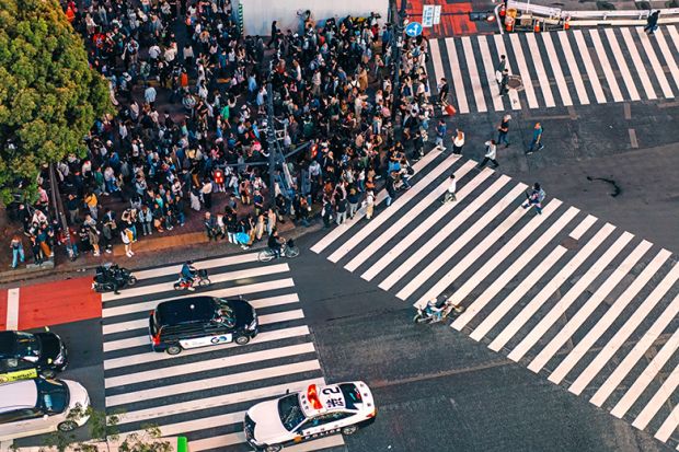 Crowd of people waiting to cross at Shibuya pedestrian crossing, Tokyo, Japan. To illustrate Asian students deciding on where to study, and whether they will switch to cheaper, safer and friendlier options closer to home.