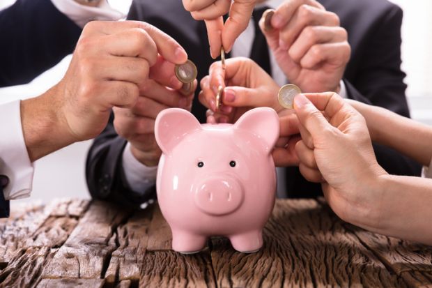 People inserting coins into piggybank