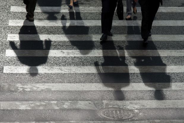People's shadows cast on road crossing People's shadows cast on road crossing
