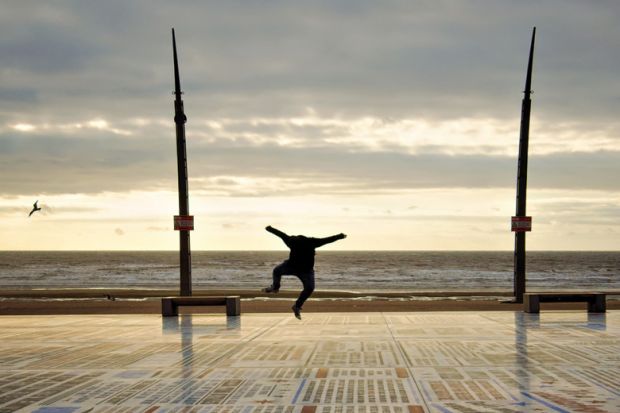 Person jumping for joy on seafront promenade Person jumping for joy on seafront promenade