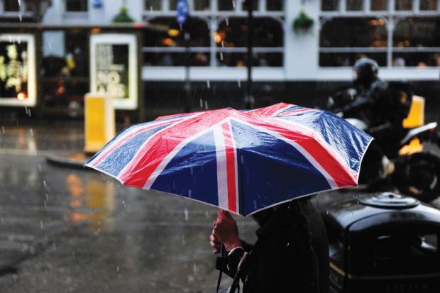 Person walking in rain carrying Union Jack umbrella Person walking in rain carrying Union Jack umbrella