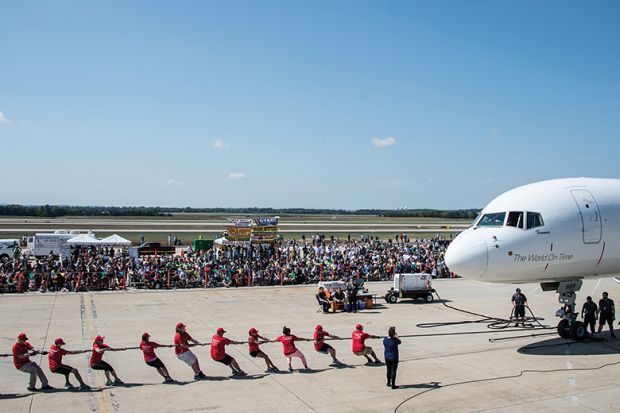 People pull plane on runway