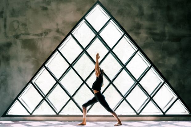 woman doing yoga by large triangular window woman doing yoga by large triangular window