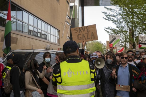 Policeman in front of protesters at student demonstration for Palestine at the University of Amsterdam Policeman in front of protesters at student demonstration for Palestine at the University of Amsterdam