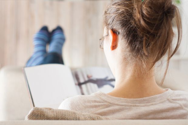 A woman reading a book with her feet up A woman reading a book with her feet up