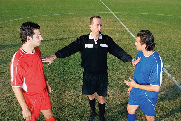 Referee between two footballers