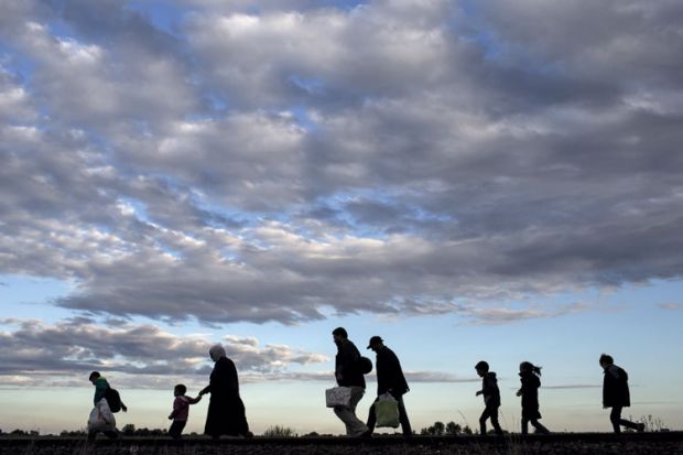 Refugees walking across a field Refugees walking across a field