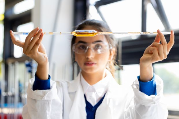 An Asian student holds a pipette level, symbolising equlaity in international collaboration 