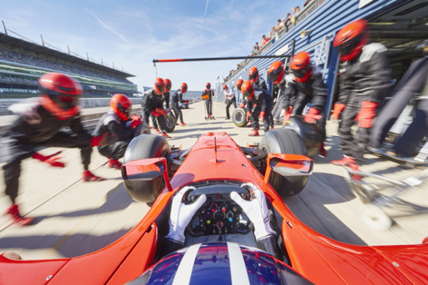 Technicians change the tyres of a racing car, symbolising support for spinouts