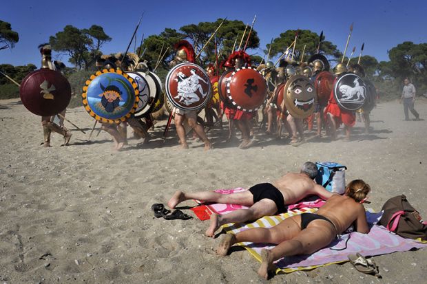 Sunbathers watch Italian re-enactors dressed as Greek hoplites perform the 490 BC battle of Marathon Sunbathers watch Italian re-enactors dressed as Greek hoplites perform the 490 BC battle of Marathon