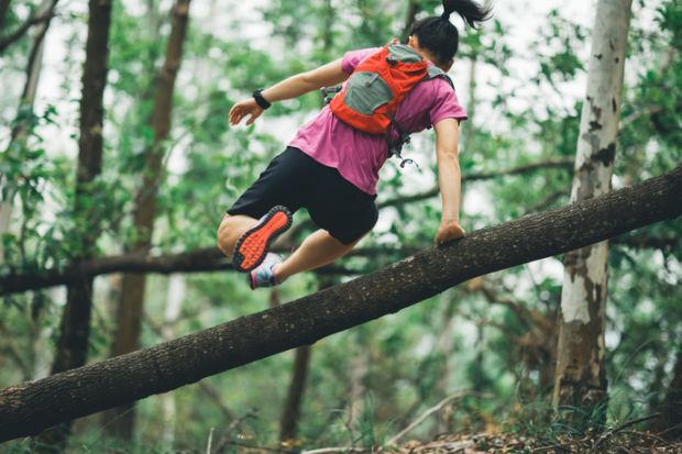 Sportswoman cross country trail running in forest