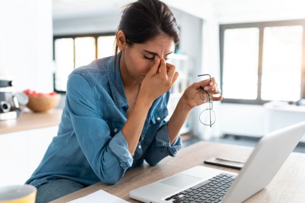 stressed woman working from home on laptop looking worried, tired and overwhelmed