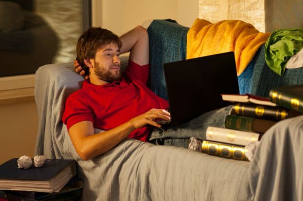 Student on laptop surrounded by books