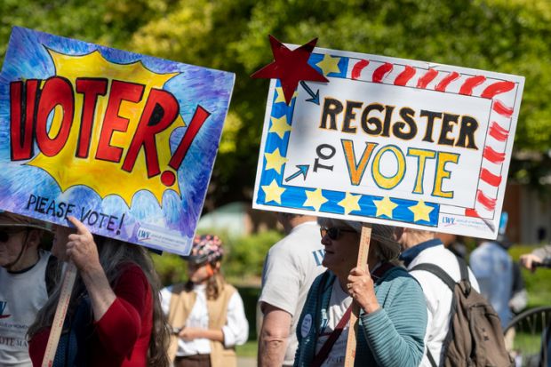People with signs encouraging people to vote People with signs encouraging people to vote