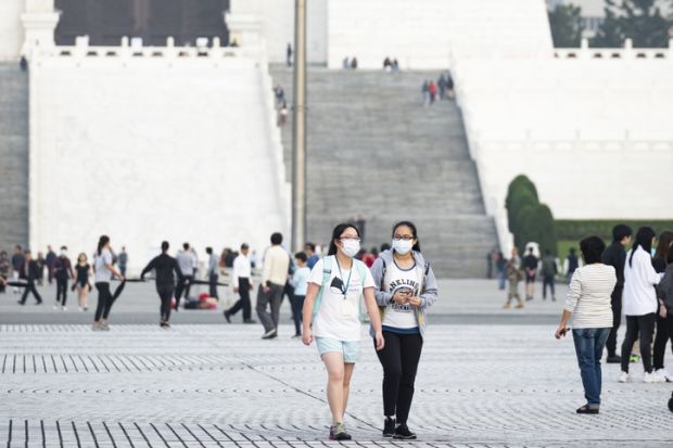 Taipei, Taiwan, March 2, 2020. Two Taiwanese girls, wearing a face mask to protect themselves from the novel coronavirus are walking in the Liberty Square, Taipei, Taiwan.