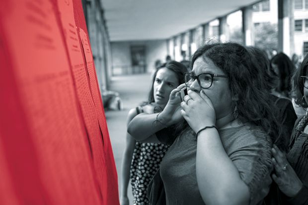 A woman on a mobile phone looks anxiously at a set of results on a board A woman on a mobile phone looks anxiously at a set of results on a board