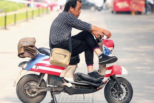 A Chinese man sits on a scooter decorated with America's Stars and Stripes outside a restaurant in Beijing on May 7, 2018. A Chinese man sits on a scooter decorated with America's Stars and Stripes outside a restaurant in Beijing on May 7, 2018.
