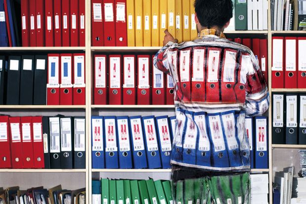 Man wearing camouflage suit matching shelves of folders