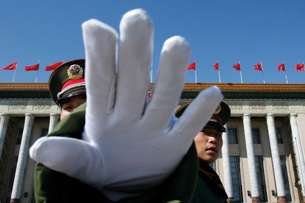 A Chinese paramilitary policeman gestures towards a photographer to stop taking pictures while standing guard at the Great Hall of the People, Beijing A Chinese paramilitary policeman gestures towards a photographer to stop taking pictures while standing guard at the Great Hall of the People, Beijing