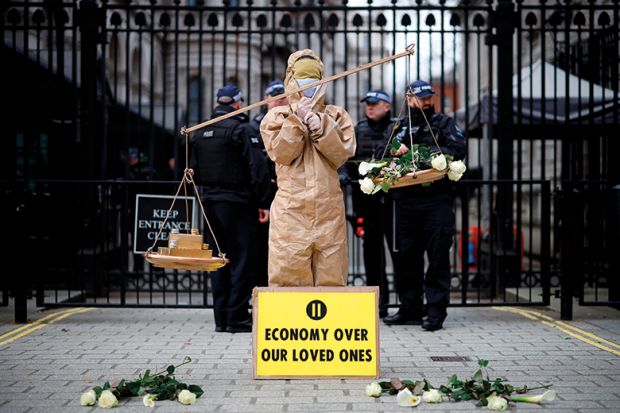 A protester from the group "Pause The System" stands beside the entrance to Downing Street in central London on March 17, 2020. A protester from the group "Pause The System" stands beside the entrance to Downing Street in central London on March 17, 2020.