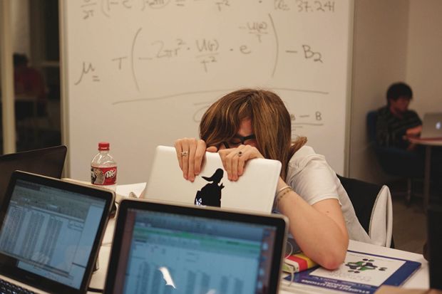 A student hides behind her laptop A student hides behind her laptop