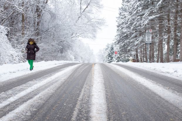 Toronto Ontario Canada Woman walking down a rural road covered with snow