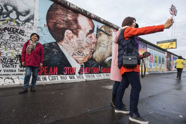 Tourists pose in front of Dmitri Vrubel mural, Berlin Wall Tourists pose in front of Dmitri Vrubel mural, Berlin Wall