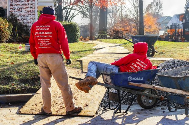 Tulsa USA Nov 15 2017 Construction workers waiting around at residential work site - one is lying in a wheel barrrow or construction cart in winter