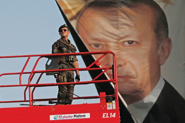 Turkish police officer standing in front of poster of President Recep Tayyip Erdoğan Turkish police officer standing in front of poster of President Recep Tayyip Erdoğan