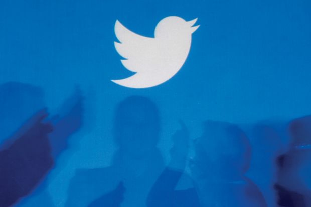 Twitter logo above silhouettes of people in discussion Twitter logo above silhouettes of people in discussion