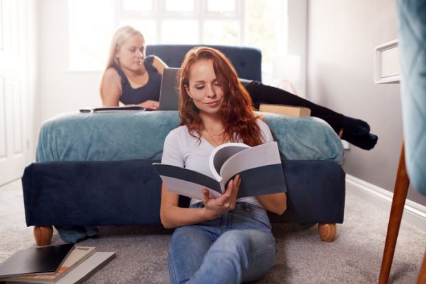 Two Female College Students In Shared House Bedroom Studying Together