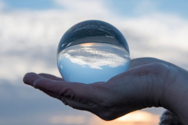 Hand holding a glass globe with a reflection of a sunset Hand holding a glass globe with a reflection of a sunset