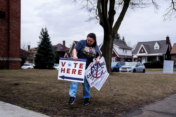 A volunteer places a "Vote Here" sign outside a polling station at McDonald Elementary School in Dearborn, Michigan A volunteer places a "Vote Here" sign outside a polling station at McDonald Elementary School in Dearborn, Michigan