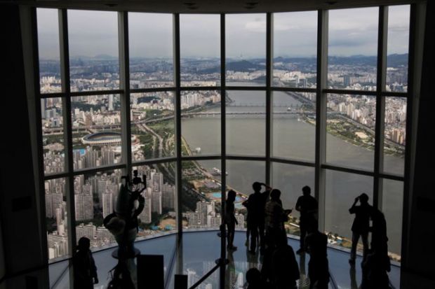 Visitors are silhouetted as they take photographs at the glass-bottomed Seoul Sky observation deck Visitors are silhouetted as they take photographs at the glass-bottomed Seoul Sky observation deck to illustrate UK university explores options in South Korea’s forgotten hub