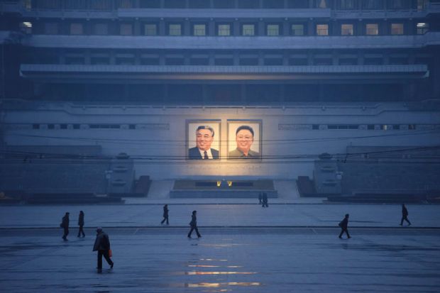  Pedestrians walking past the portraits of late North Korean leaders Kim Il Sung and Kim Jong Il across Kim Il Sung square as a metaphor for article offers rare look inside a North Korean university