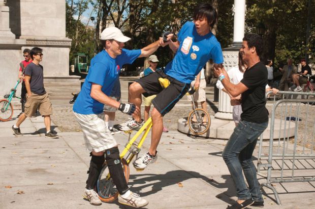 Unicyclist stumbles with two people supporting him Unicyclist stumbles with two people supporting him to illustrate uncertainty on wait lists as US colleges face enrolment disruption
