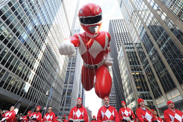 Giant inflatable Power Rangerheld by people walking behind in New York City. Giant inflatable Power Rangerheld by people walking behin as a metaphor for Alumni-led boards ‘key to US universities’ strength’