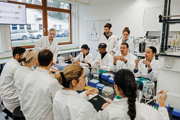 A group of students and a medical tutor working on a DNA experiment together to illustrate Team research pilot tackles dominance of principal investigators